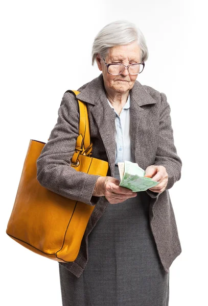 Seniorin zählt Geld, während sie vor weißem Hintergrund steht — Stockfoto