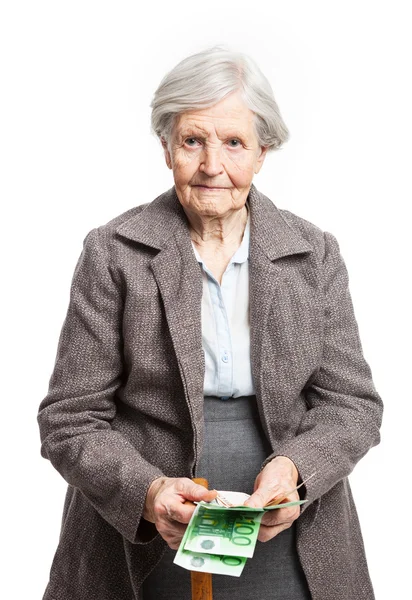 Seniorin zählt Geld, während sie vor weißem Hintergrund steht — Stockfoto