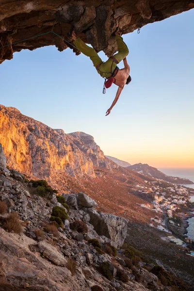 Hombre escalador en roca colgante contra hermosa vista de la costa por debajo —  Fotos de Stock