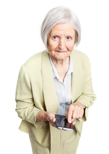 Mujer mayor sosteniendo el teléfono móvil y mirando a la cámara sobre blanco — Foto de Stock