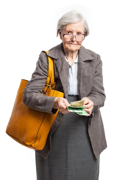 Старшая женщина считает деньги, стоя на белом фоне — стоковое фото