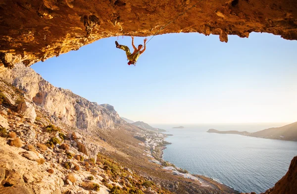 Hombre escalador acaba de caer de un acantilado mientras escalaba en roca. Hermosa vista de la costa en el fondo . — Foto de Stock