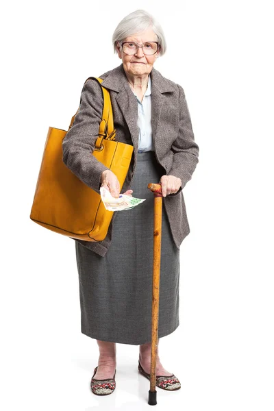 Seniorin hält Geld in der Hand, während sie vor weißem Hintergrund steht — Stockfoto