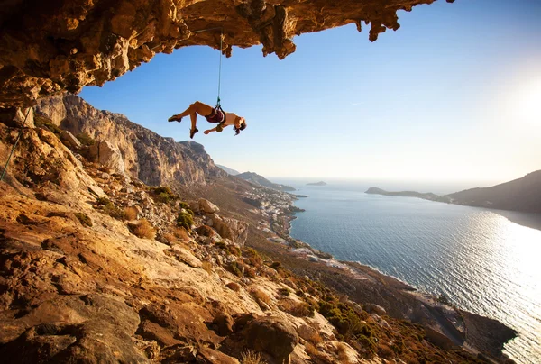 Female rock climber hanging on rope after unsuccessful attempt to take next handhold on cliff while lead climbing — Stock Photo, Image