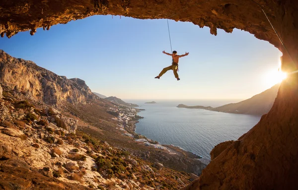 Rock climber hanging on rope while lead climbing at sunset — Stock Photo, Image