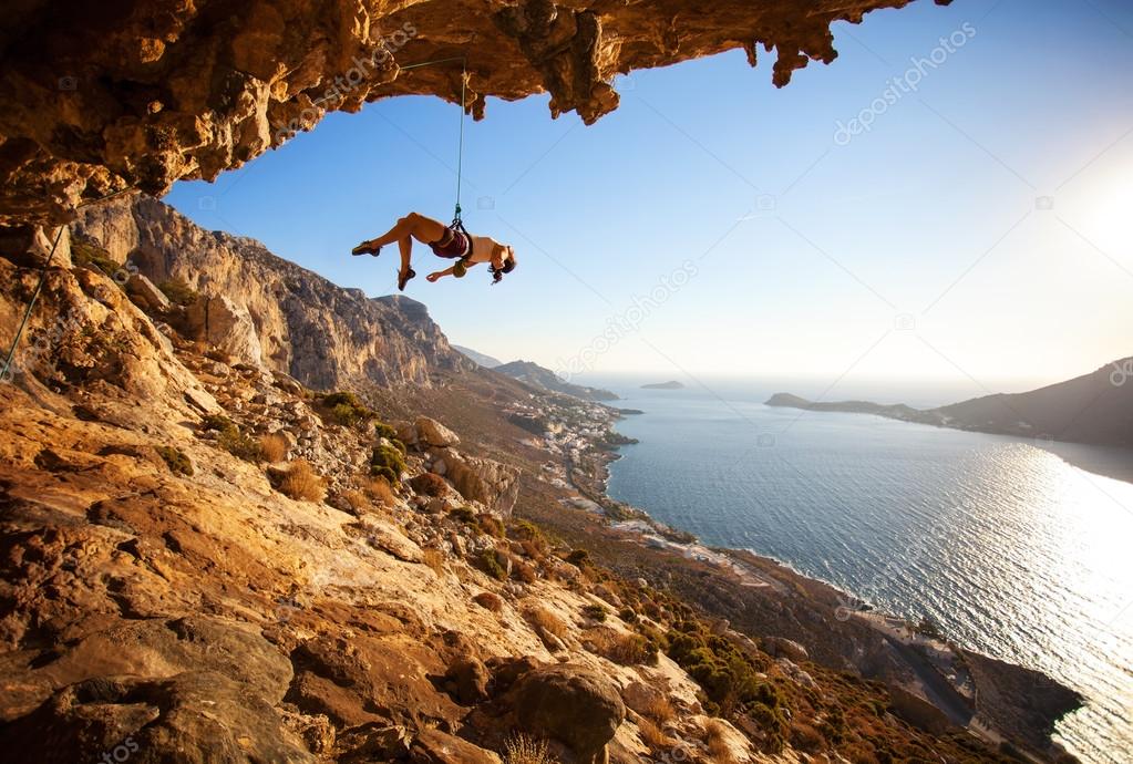 Female rock climber hanging on rope after unsuccessful attempt to take next handhold on cliff while lead climbing