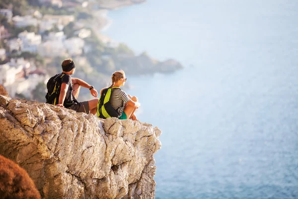 Young couple sitting on rock and enjoying view — Stock Photo, Image