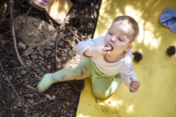 Little boy biting cone sitting on touristic mat