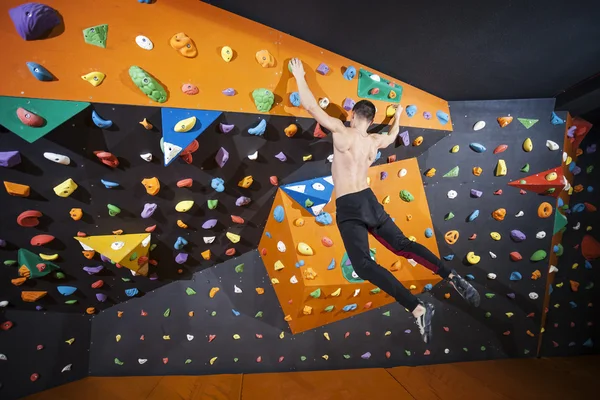 Člověk cvičí bouldering v krytý horolezectví tělocvičny — Stock fotografie