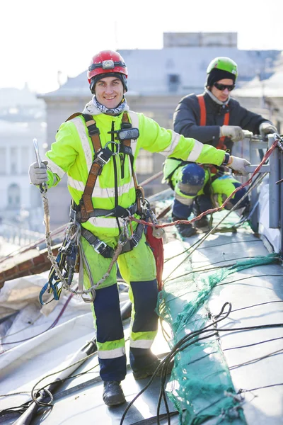 Alpinistas industriais que trabalham no telhado do edifício — Fotografia de Stock