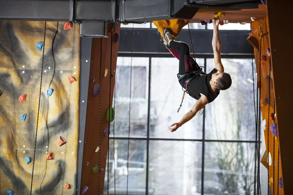 Junger Mann übt Klettern in Kletterhalle — Stockfoto