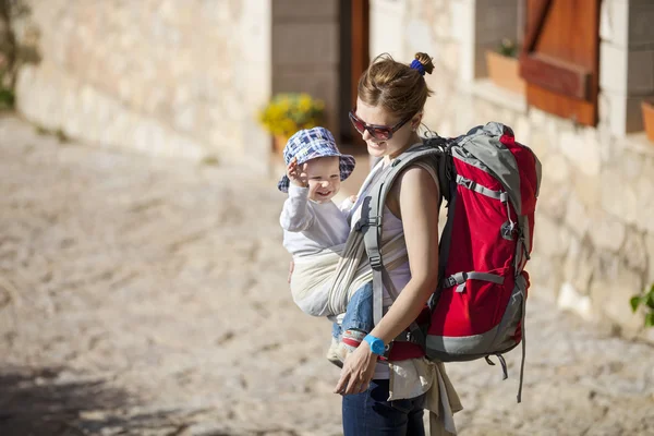 Arkadan kovalayan küçük oğlunu taşıyan kadın turist — Stok fotoğraf