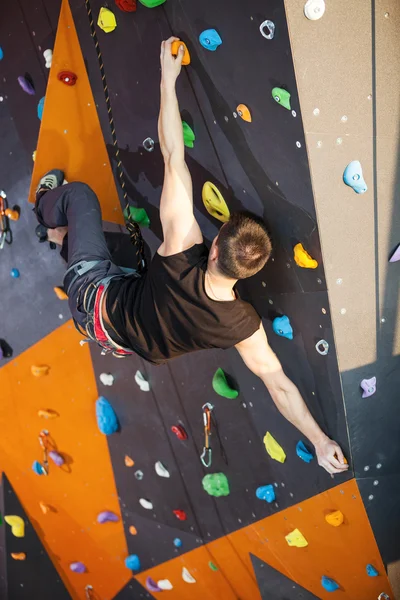 Ung man öva bergsklättring i klättring gym — Stockfoto