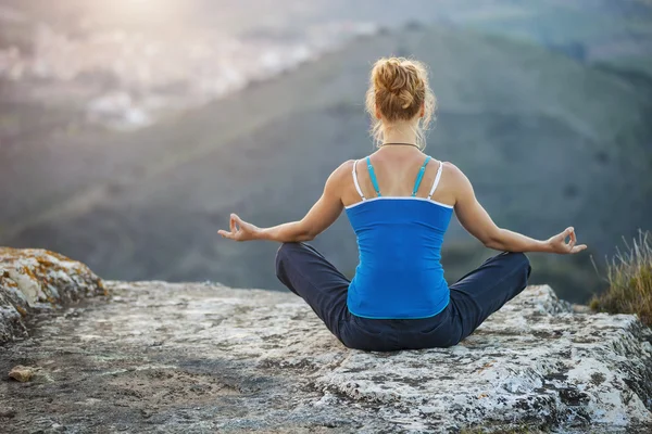 Young woman sitting in asana position on a rock — Stock Photo, Image