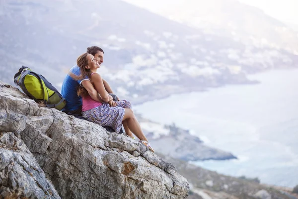 Pareja joven sentada en la roca y disfrutando de una hermosa vista — Foto de Stock