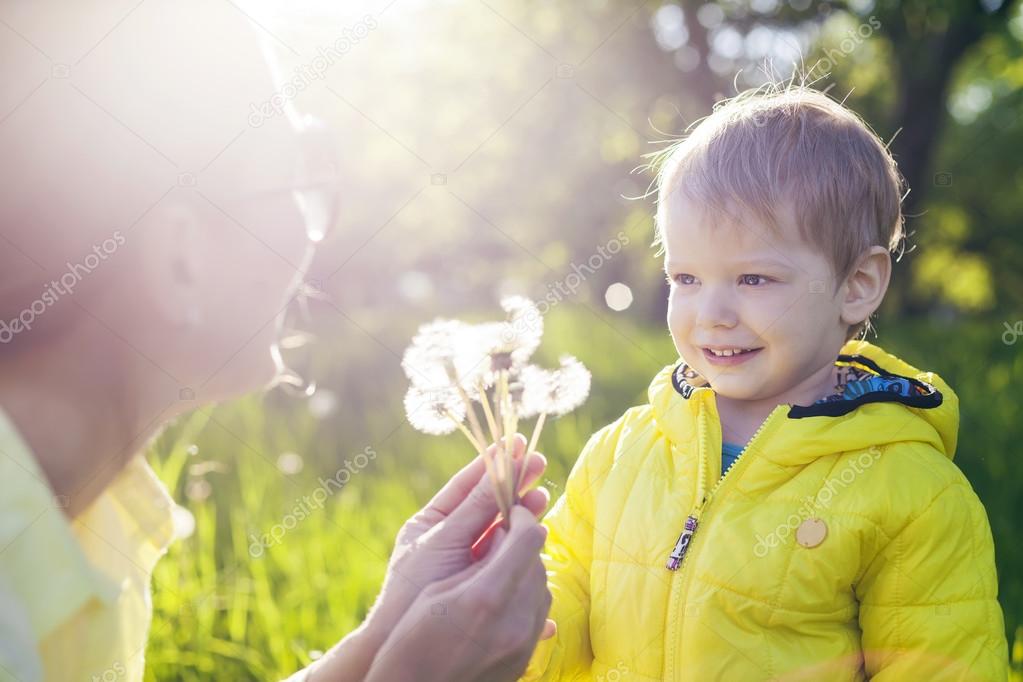 Boy making a wish before blowing dandelions