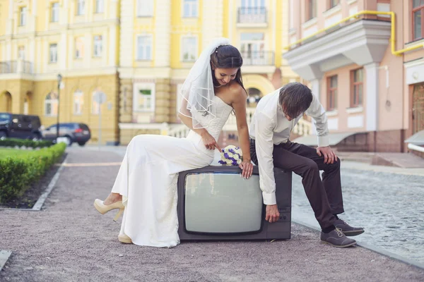 Newlyweds sitting on retro tv set — Stock Photo, Image