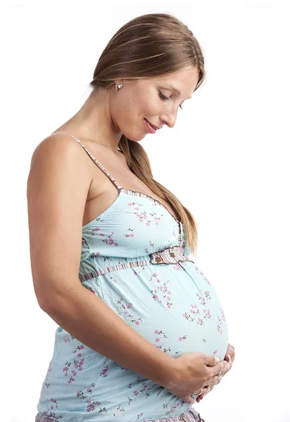 Mulher grávida sorrindo enquanto olha para a barriga — Fotografia de Stock