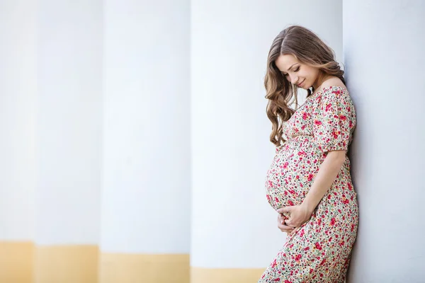 Kobieta w ciąży opierając się kolumna — Zdjęcie stockowe