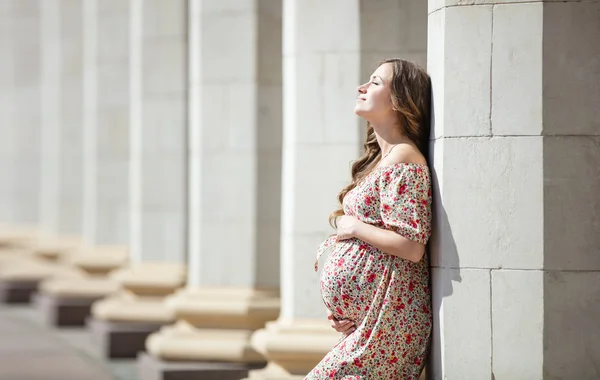Беременная женщина возле колонны — стоковое фото