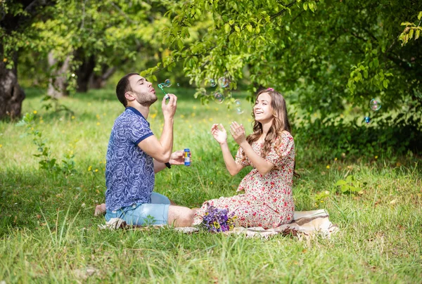 Těhotná žena s manželem vyfukuje bubliny — Stock fotografie