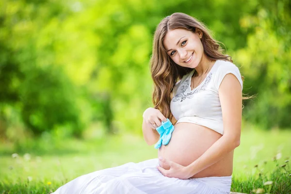 Femme enceinte tenant des chaussons de bébé — Photo