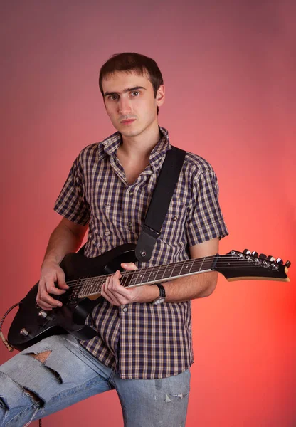 Виразний Молодий Чоловік Грає Гітарі Червоному Тлі Музикант Прекрасному Залі — стокове фото