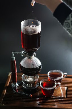 Puer tea in the siphon, shallow DOF, on black background clipart