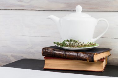 Yeşil Beyaz demlik bitki çayı üzerinde eski kitaplar bırakır.