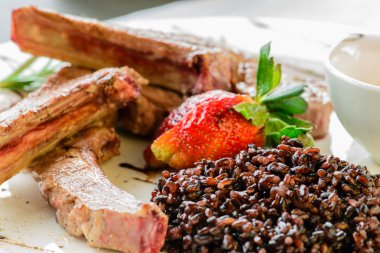 Koyun eti sıcak tabak kaburga, kahverengi pirinç, taze strawb ile dekore edilmiş