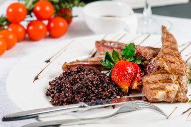 Koyun eti sıcak tabak kaburga, kahverengi pirinç, taze strawb ile dekore edilmiş