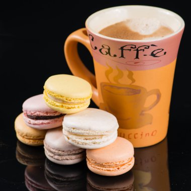 Yüksek fincan cappuccino kahve ve siyah bir zemin üzerine acıbadem kurabiyesi