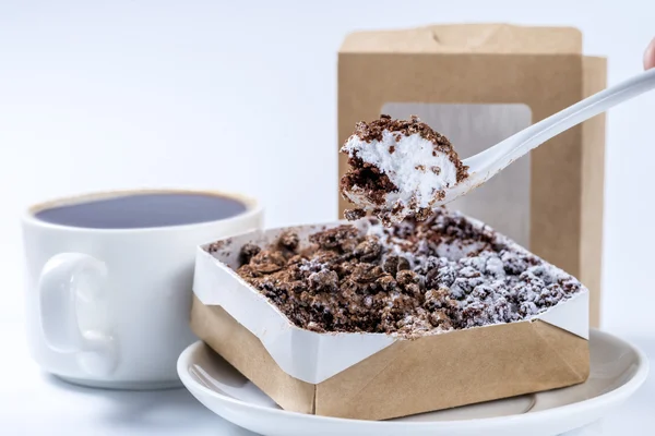 Piece of cake on a spoon close-up on a background of coffee cups — Stock Photo, Image