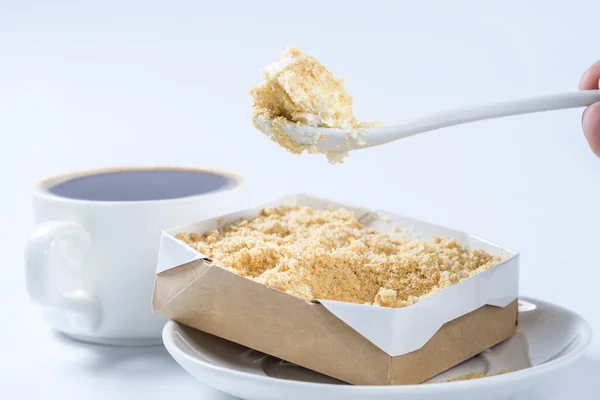 Piece of cake on a spoon close-up on a background of coffee cups — Stock Photo, Image