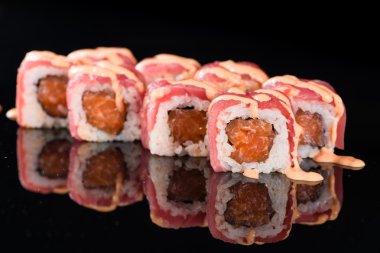 Yansıması ile siyah arka plan üzerinde suşi rulo ile Somon