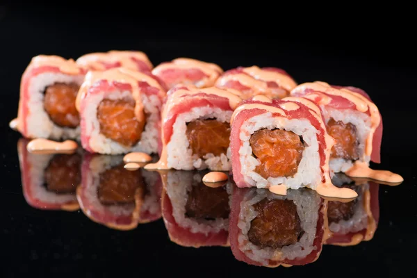 Yansıması ile siyah arka plan üzerinde suşi rulo ile Somon