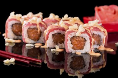 Suşi Roll somon ve zencefil üzerinde siyah arka plan ile