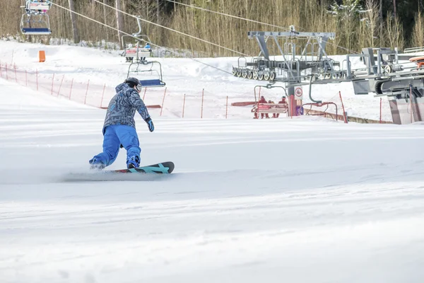 Homem snowboard em uma estância de esqui em um dia ensolarado — Fotografia de Stock