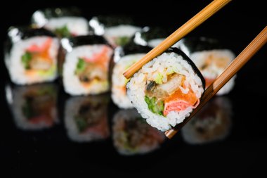 masada suşi roll bölümünü alarak yemek çubukları, yakın çekim