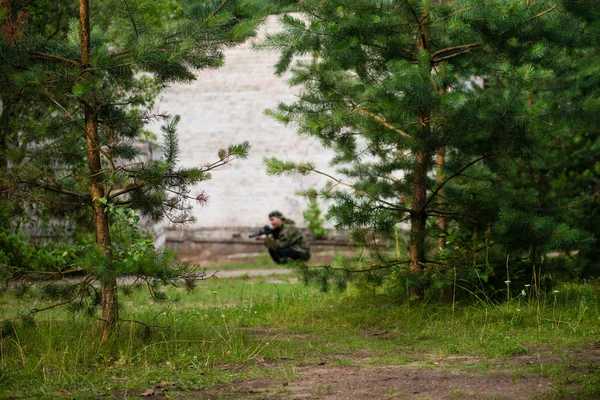 laser tag game, soldiers with guns blurred behind trees