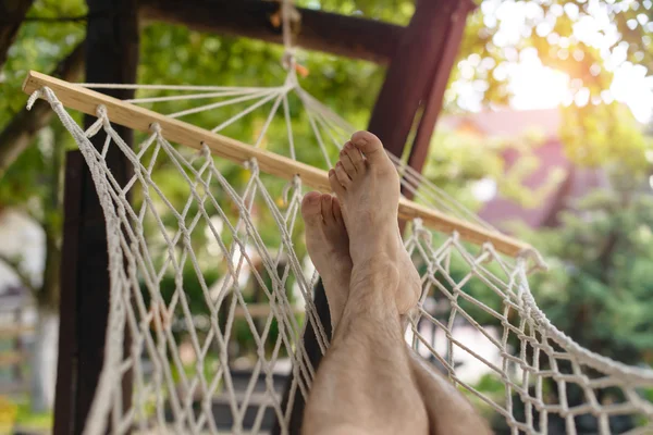 Голі ноги в гамаку у відпустці, вузька глибина різкості — стокове фото