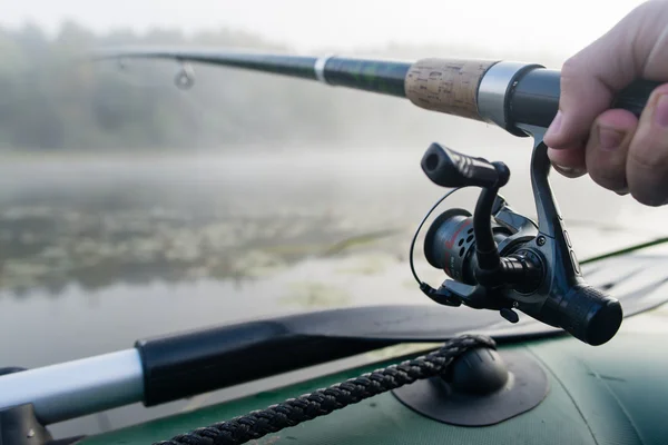 Close-shot de mãos humanas segurando uma vara de pesca em primeiro plano — Fotografia de Stock