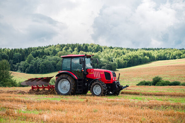 Red Tractor Plowing in Autumn, Farmer plowing stubble field in tractor preparing plows the land, agricultural works at farmlands, agriculture tractor-landscape