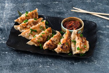 Geleneksel Asya tavası kızartılmış sos soslu gyoza köftesi, seramik tabakta et ve mantarlı japon gyoza köftesi.