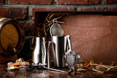 Kokteyl yapmak için çelik bar aletleri. Titretici, jigger, süzgeç, kaşık, ahşap zemin üzerinde kopyalama alanı olan bar aksesuarları