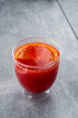 Baharatlı greyfurt bitkisel çayı ve gri arka planda cam bardakta bal, portakallı kırmızı içecek, geleneksel Japon içeceği.