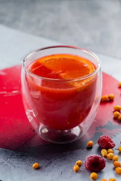 Chá de ervas de toranja com especiarias e mel em copo de vidro em um fundo cinza, bebida quente vermelha com laranja, uma bebida tradicional japonesa — Fotografia de Stock