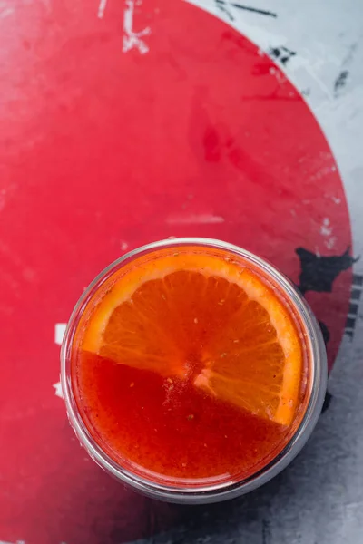 Грейпфрутовый травяной чай со специями и медом в стеклянной чашке на сером фоне, красный горячий напиток с апельсином, японский традиционный напиток — стоковое фото