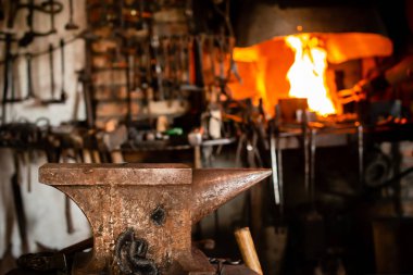 Demirci aletleri, çekiç ve örs eski demirci atölyesinde, eski bir zanaat, eski bir demirci ocağı ve bir sürü demirci teçhizatı ile yanmış.