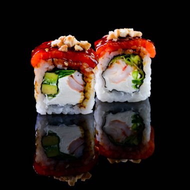 Asya mutfağı kavramı. Japon menü kafesi, restoranı ve suşi barı için siyah arka planda farklı doldurulmuş iki rulo suşi. Yansıması olan iki suşi rulosu.